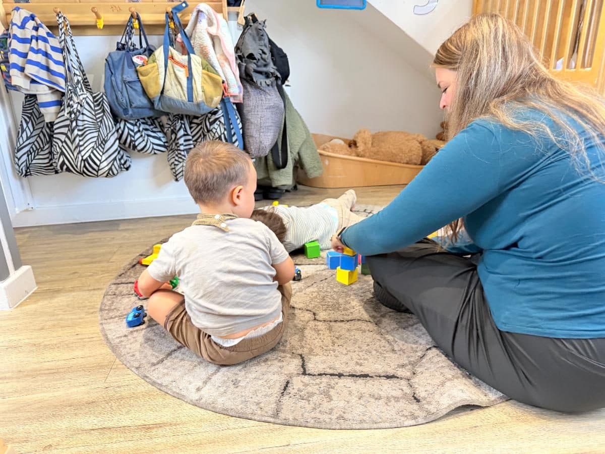 Unique child montessori practitioner playing with toddler blocks