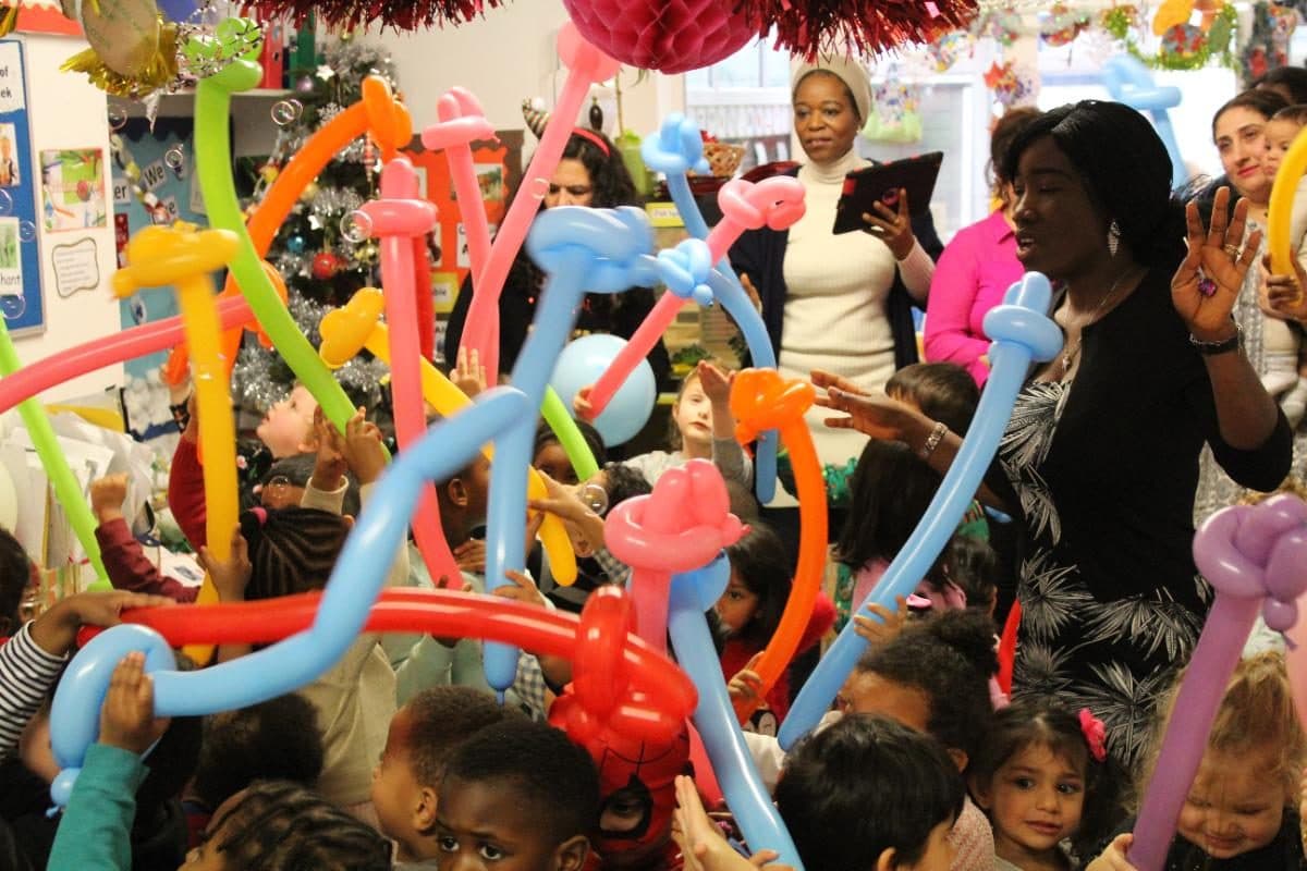 Children and practitioners celebrating with colourful decorations at unique child montessori northolt